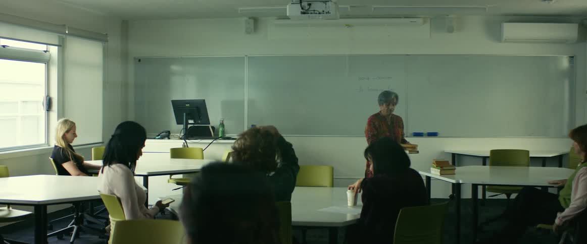 Students sit down and settle in as a teacher gets ready for class