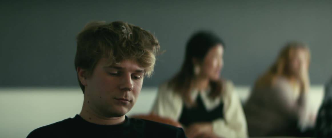 Student with black sweater sits at desk looking down waiting for lecture in class