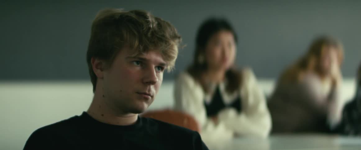 College students sitting at desks listen to professor giving lecture in class