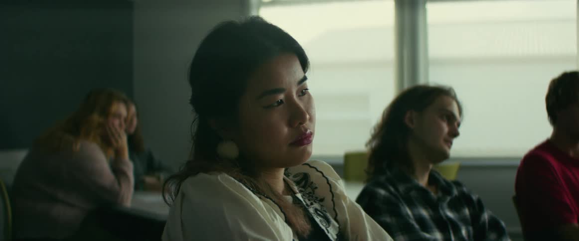 University students talk while sitting in classroom waiting at tables