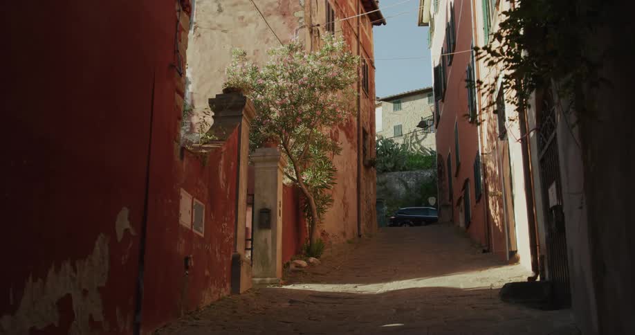 A car is parked at the end of a pretty european road between buildings