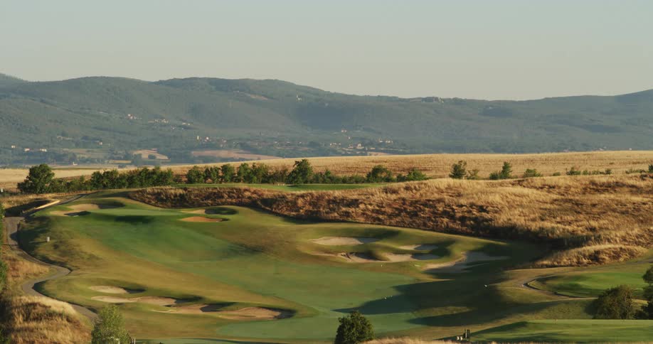 A golf course sprawls out in a remote area near mountains