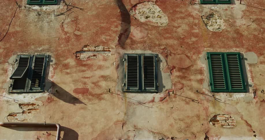 Static shot of closed windows on the decaying facade of a building