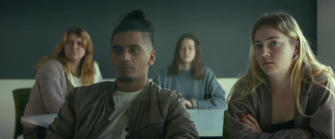 Camera slowly pans past two boredlooking students
