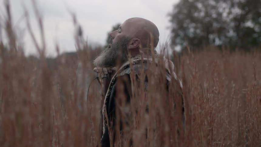 A man is kneeling in a field of tall grass