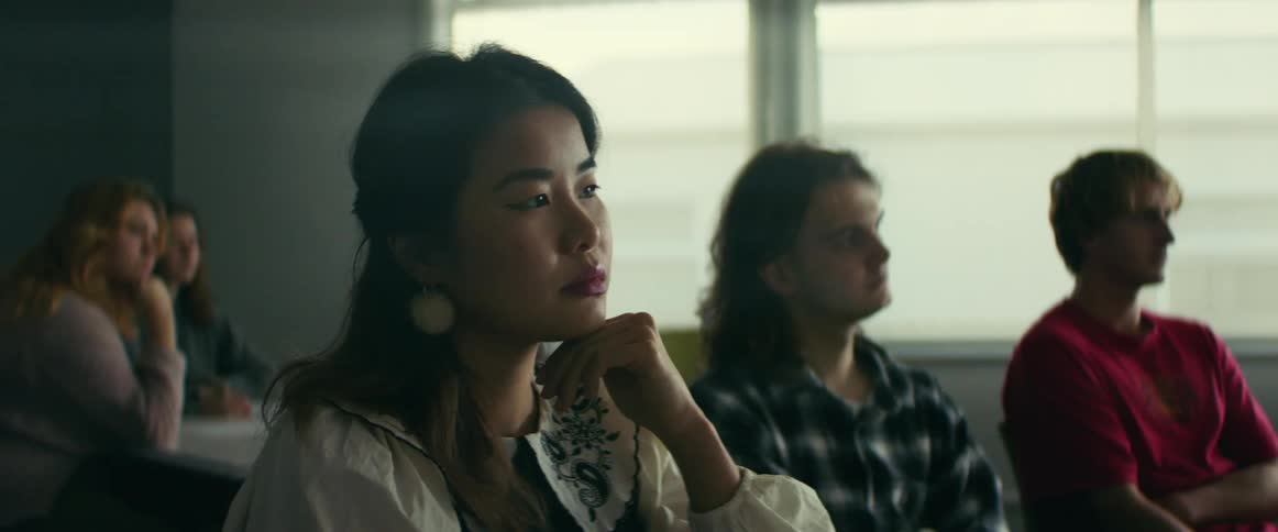 A group of students stare thoughtfully in one direction in a classroom
