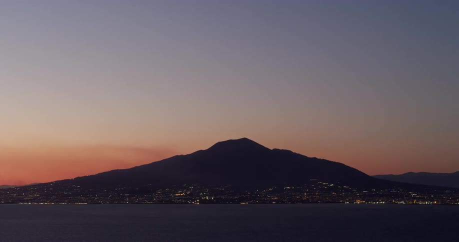 The sun setting over a mountain with city lights