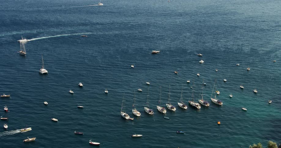 Aerial view of boats anchored in the calm blue ocean waters of a bay