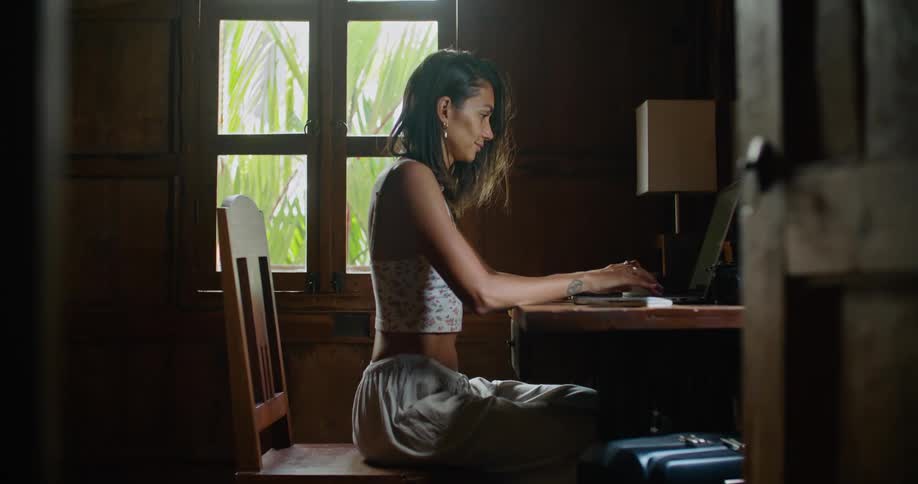 Young woman sitting at home typing on a laptop at daytime