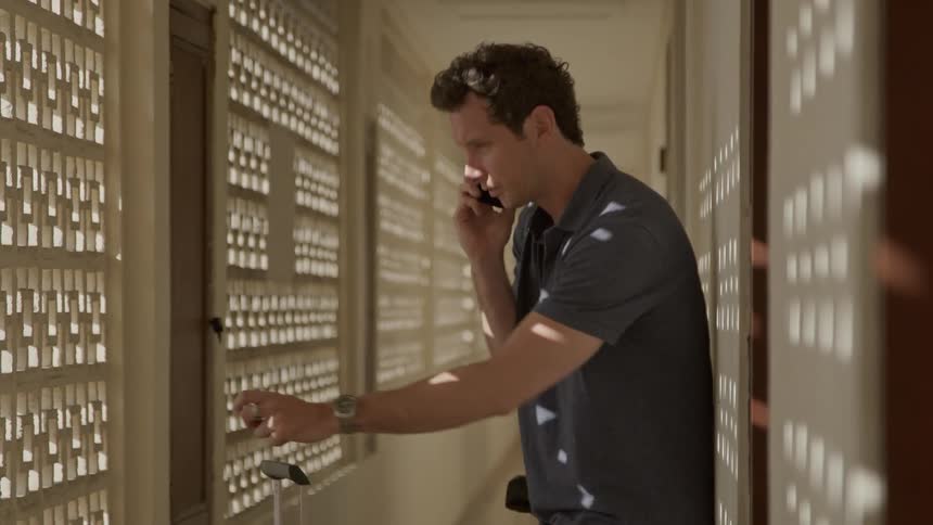 Man on telephone talks for a moment and checks his watch
