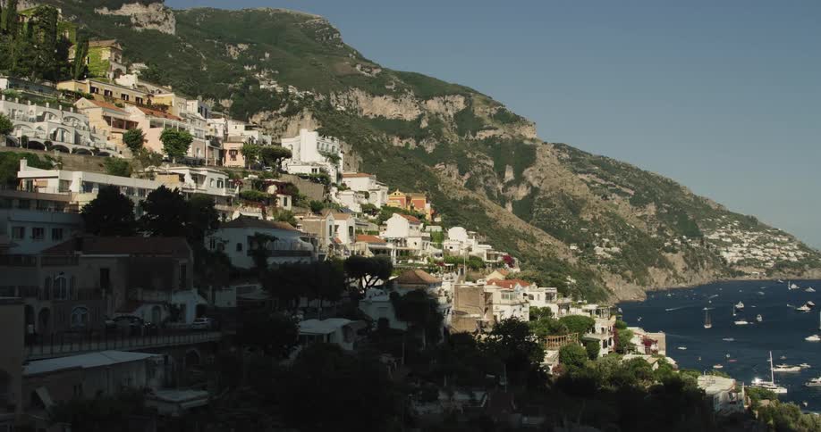 Houses of a small coastal town on the mountains next to the bay filled with boats