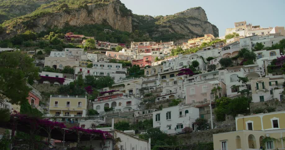 Car drives along on road near bottom of town sitting on the mountain side