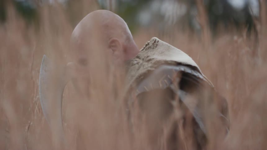 A man is kneeling by his axe in a field