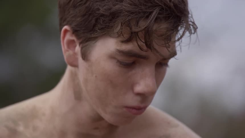 A dirty boy standing while looking down