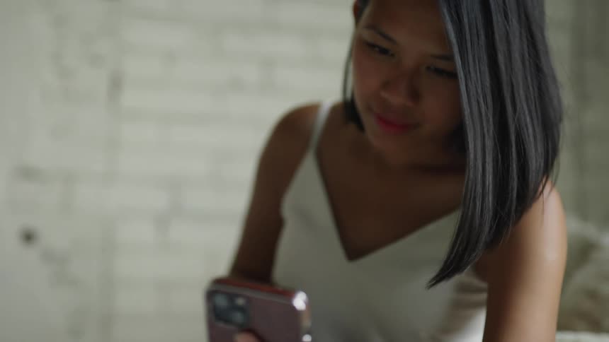 A woman pets her dog while scrolling through her phone
