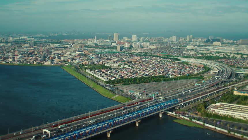 An aerial view of cars and a train traveling over an urban bridge