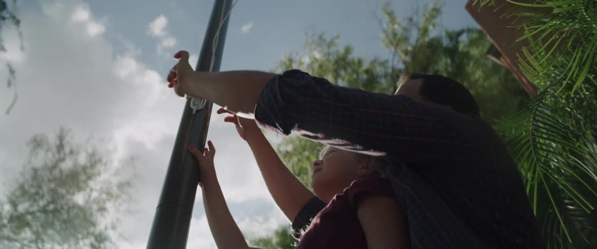 A father and daughter tie the rope on the flag pole