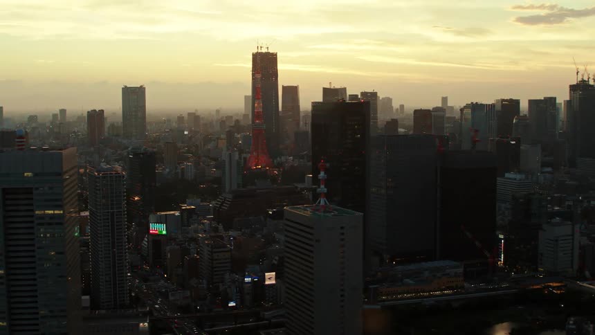 Skyscrapers and towers with digital billboards under a golden sky