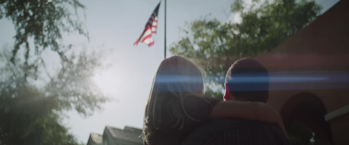 A father and daughter watch the flag