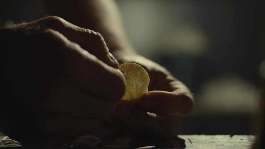A man runs a piece of string through a seashell