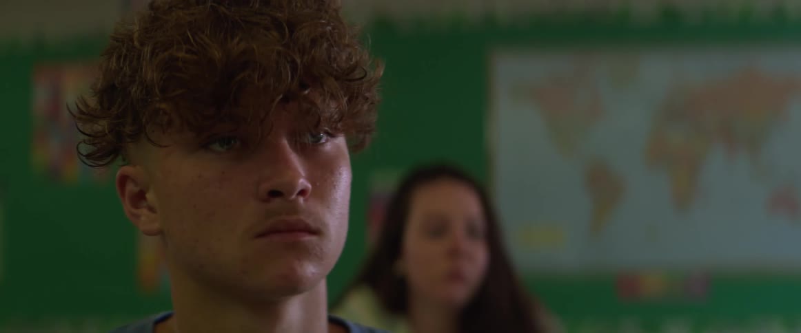 Close up on the face of students sitting in a classroom listening to the teacher