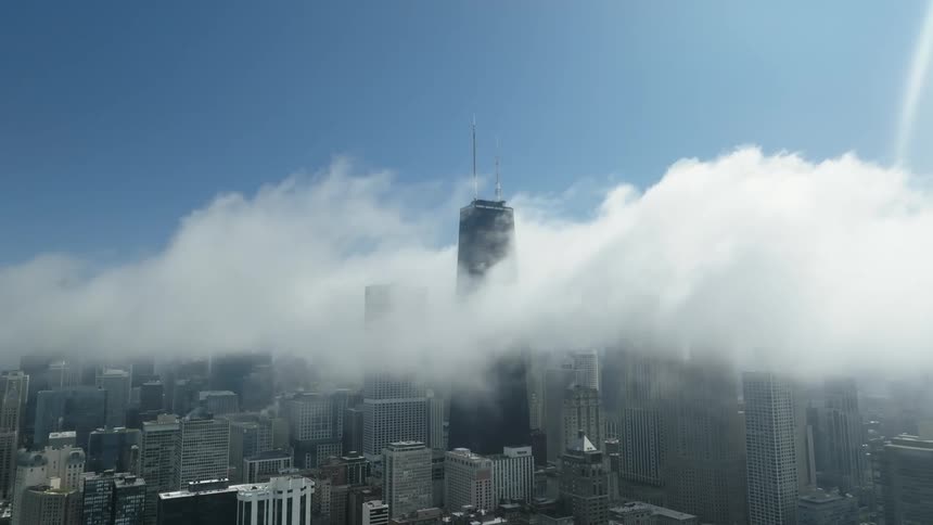 Clouds moving over a tower in a city with high rise office buildings