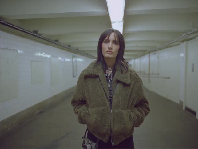 A woman is standing in a building and looking at the camera