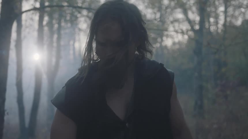 A man stands in a forest on a windy day
