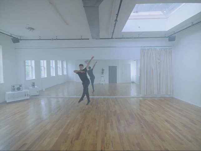 Male dancer practices alone in dance studio with a wall mirror