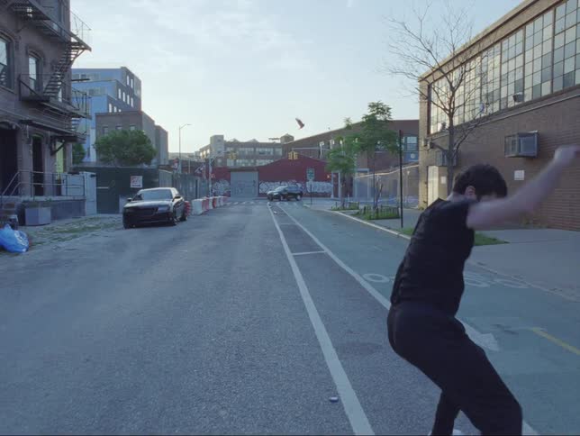 A man spins and dances on a city street turns and begins to walk away
