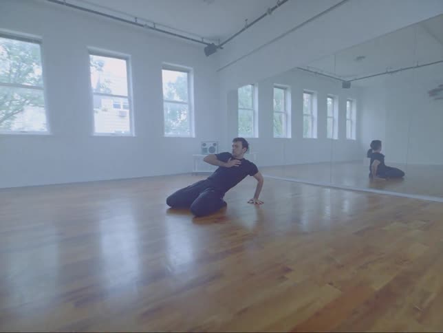 A young male dancer in a studio executes a dramatic emotional move