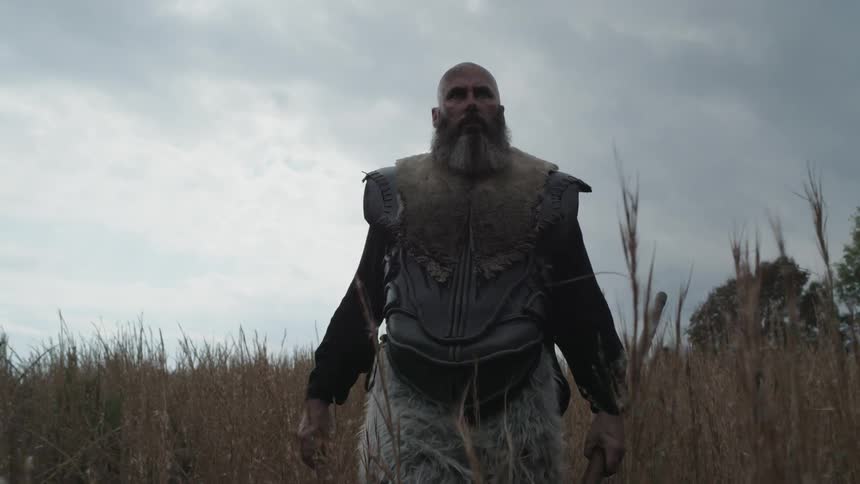 A man walks through tall grass on a cloudy day