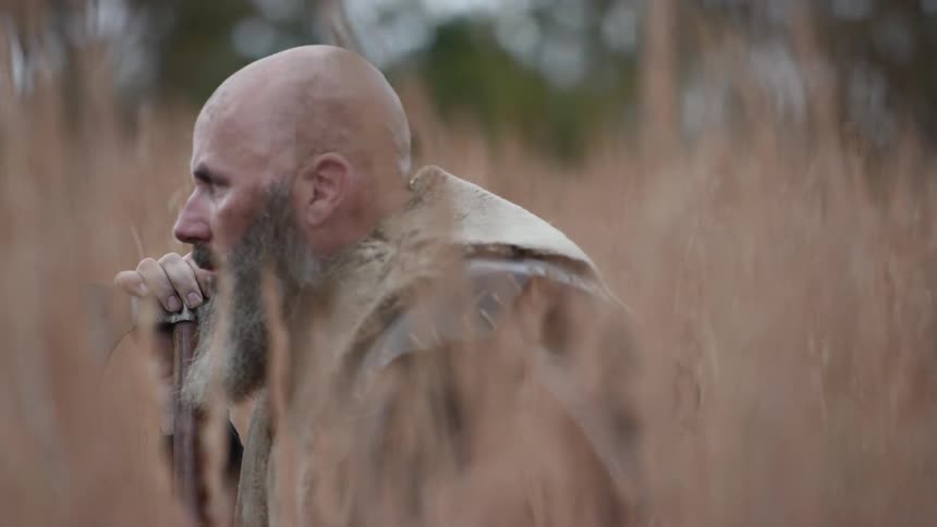 A warrior sitting in tall, dead grass