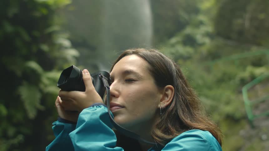 A woman taking photos with a camera in a rainforest