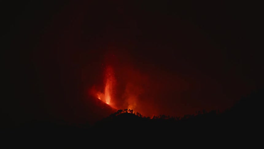 Lava and sparks are flying up into the air from a volcano as it erupts