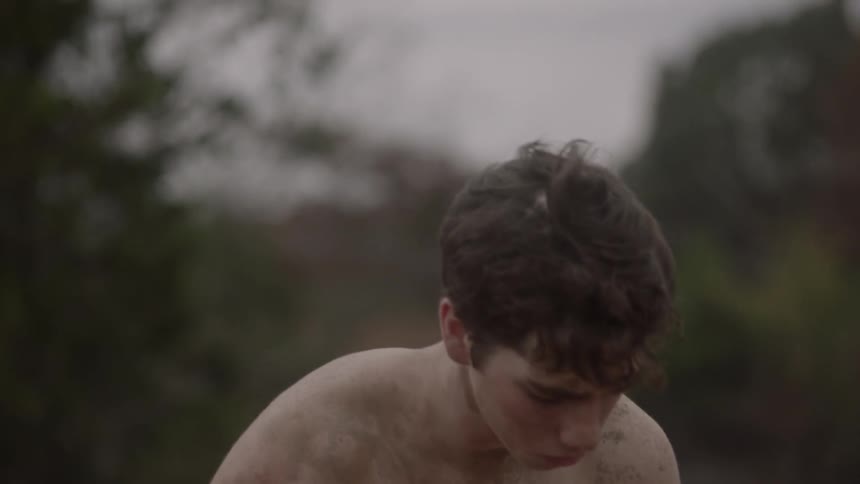 A shirtless man looks around on a windy day