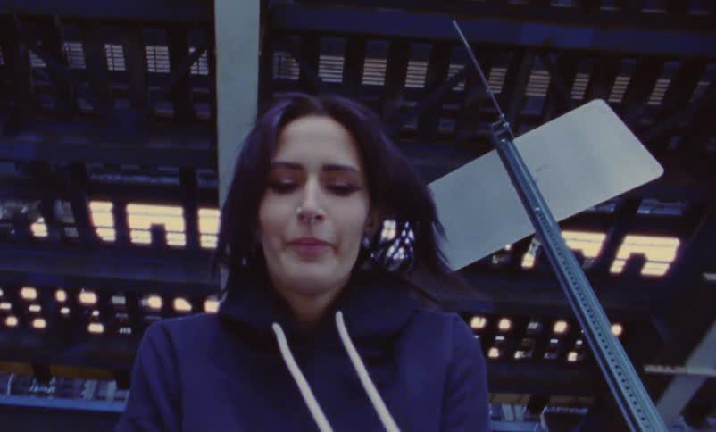 A woman is walking under a bridge in a city