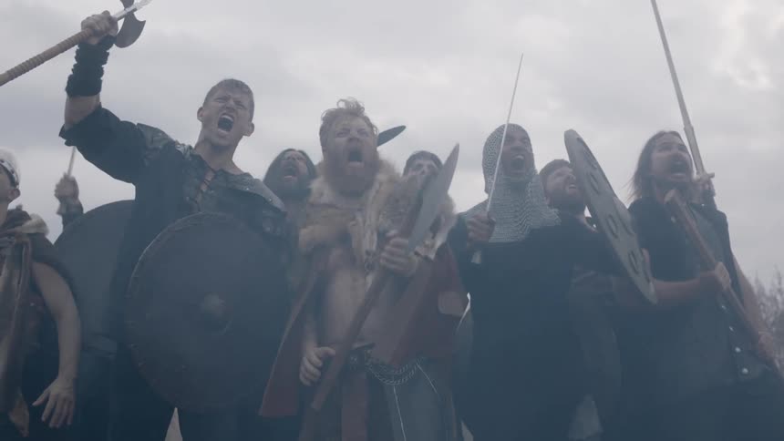 A group of men celebrate by raising arms and shouting
