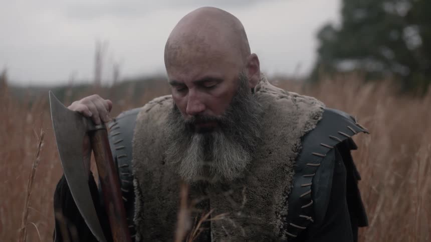 Man holding an ax sitting in a field