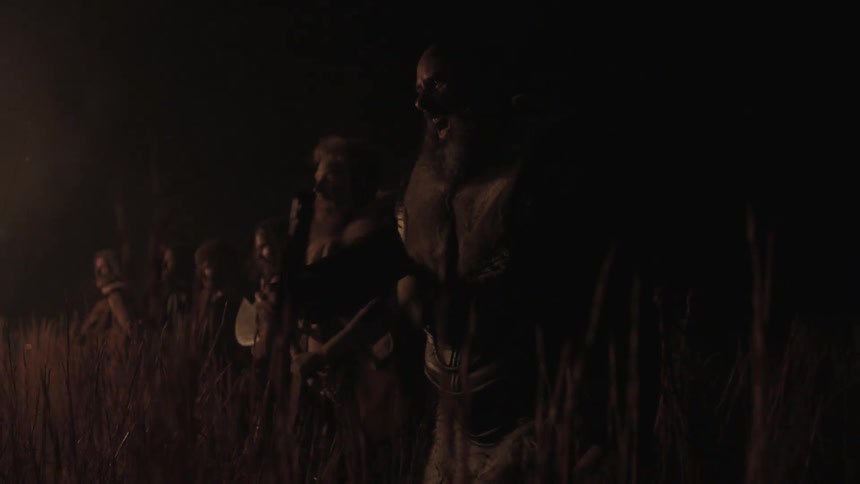 A row of people with weapons stand in a line at night