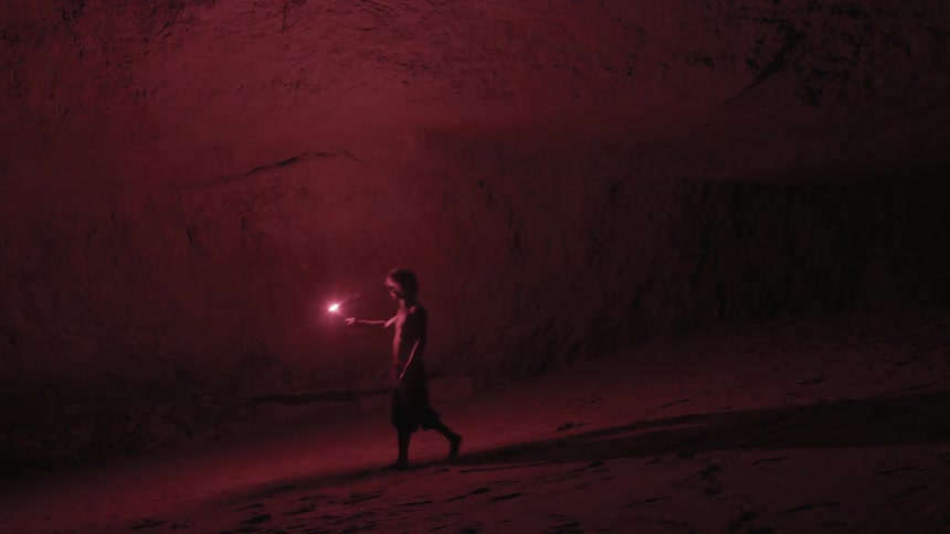 A man is searching a cave holding a flare