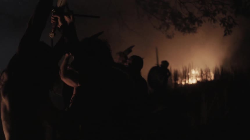 People are fighting at night near a large fire
