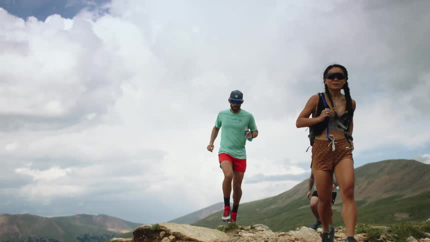 Three people jog on rocky hills