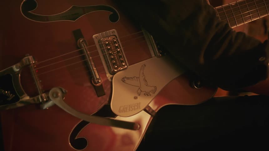 A musician holds their acoustic guitar