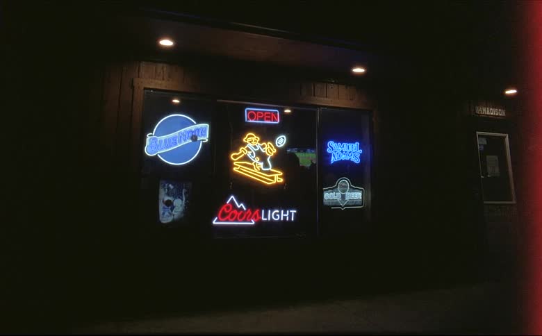 Neon brand signs in the window of a bar at night
