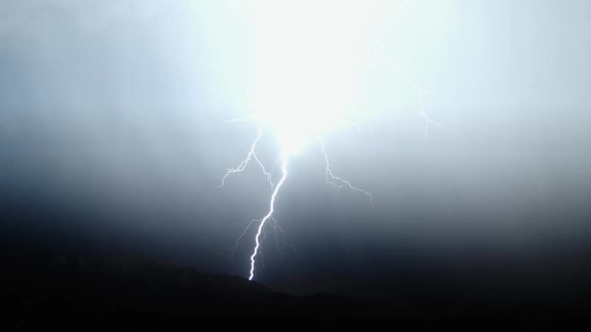Lightning flashing and striking across a black sky