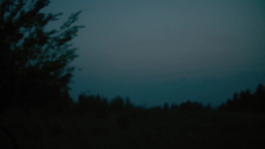 Silhouette of a female cyclist riding a bike on a rural road at night
