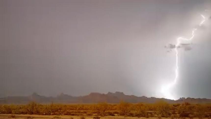 Lightning flashes through the thick clouds over a grassland in the evening