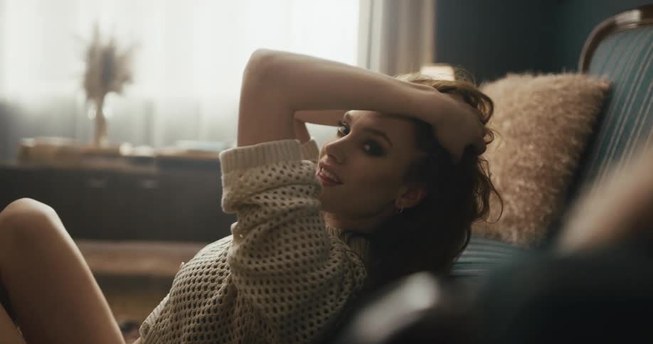 Young seductive woman sitting on the living room floor looking at the camera