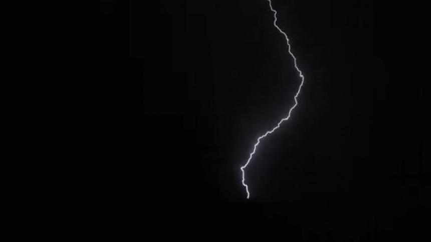 Lighting bolts move through sky and reach the ground at night